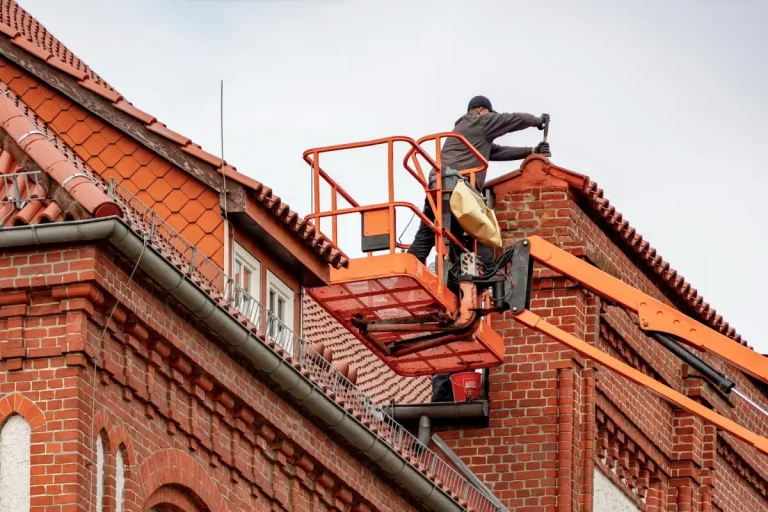 Roofer performing scheduled roof maintenance on a brick building