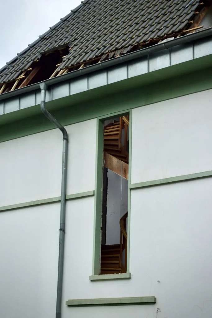 House exterior with visible storm damage to the roof and walls